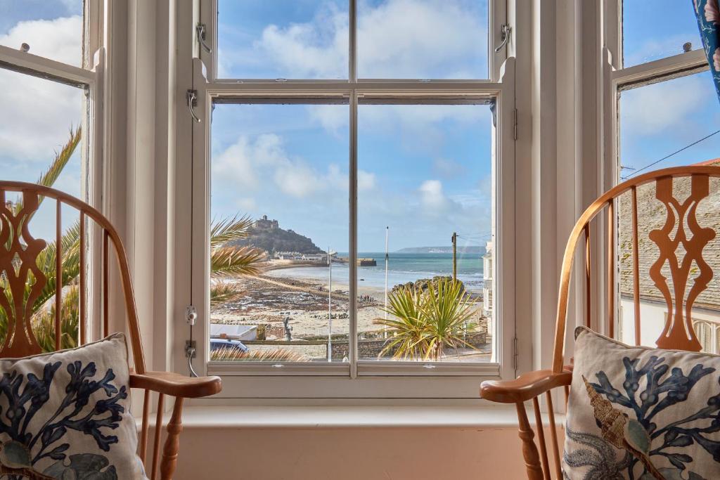马拉扎恩Ocean Villas的窗户配有椅子,俯瞰着海滩