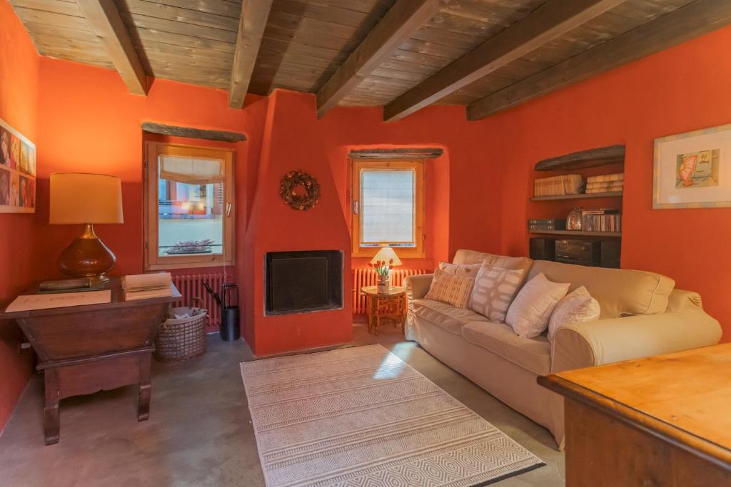 布里维奥La Corte Degli Artisti by Rent All Como的客厅设有橙色的墙壁、沙发和电视