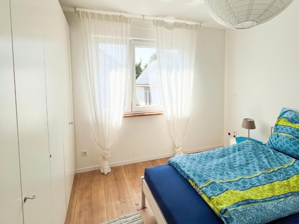 洛尔施Helle und gemütliche Ferienwohnung in Lorsch的一间卧室设有蓝色的床和窗户。