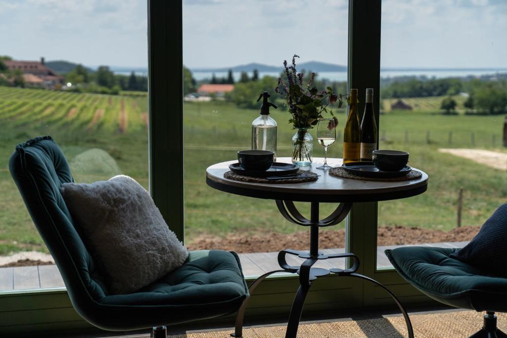 KáptalantótiIstvándy Birtok的一张桌子、两把椅子和一张桌子及酒瓶