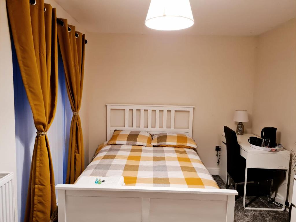 德比Mills Home Stays的一间卧室配有一张床、一张书桌和窗帘