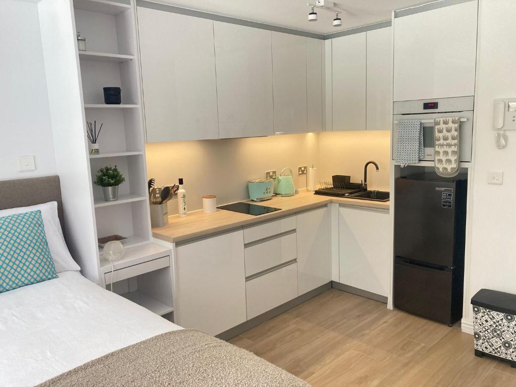 直布罗陀CP luxury studio的厨房配有白色橱柜和黑色冰箱。
