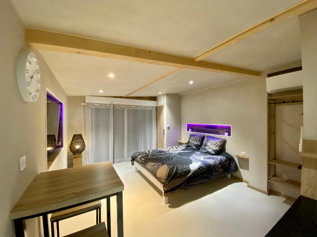 弗传斯LE COTTAGE Zen LOVE的一间卧室配有一张床、一张桌子和紫色照明