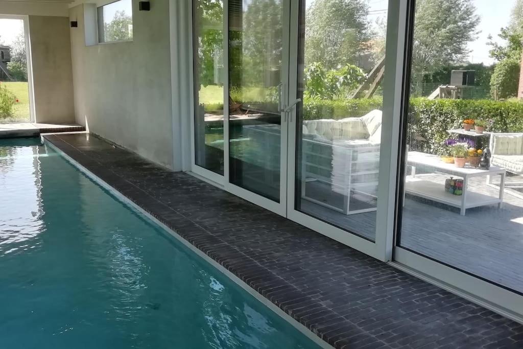 StadenDreve 14 - bovenverdieping的一座带玻璃门的别墅旁的游泳池