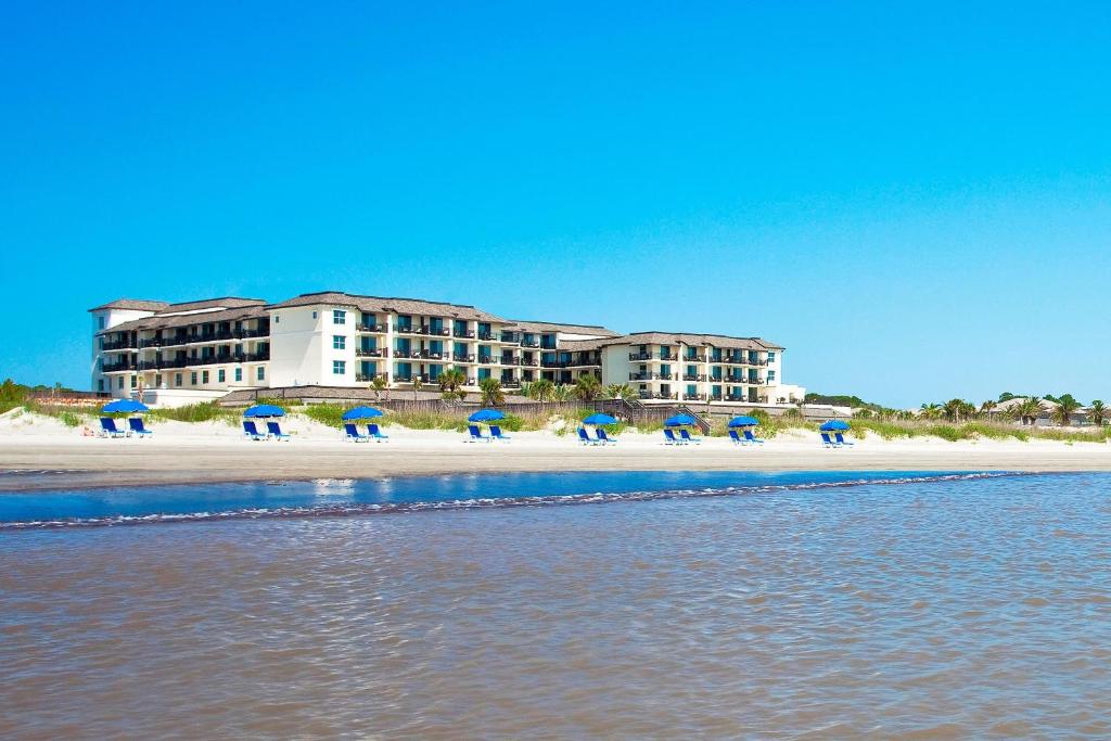 杰基尔岛The Westin Jekyll Island Beach Resort的一群人坐在海滩上,拿着遮阳伞