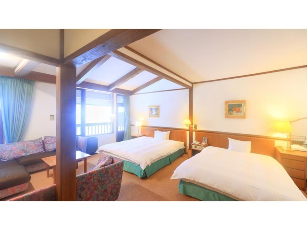 青森Sukayu Onsen Hakkoda Hotel - Vacation STAY 66845v的酒店客房,设有两张床和一张沙发