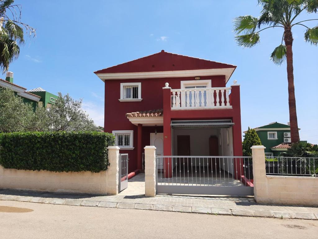 佩尼斯科拉URBANIZACION MIRAMAR PENISCOLA的红色的房子,设有白色阳台和棕榈树