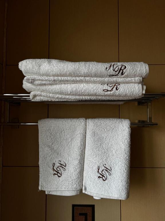 曼加利亚Hotel Rion的浴室架子上的一组毛巾