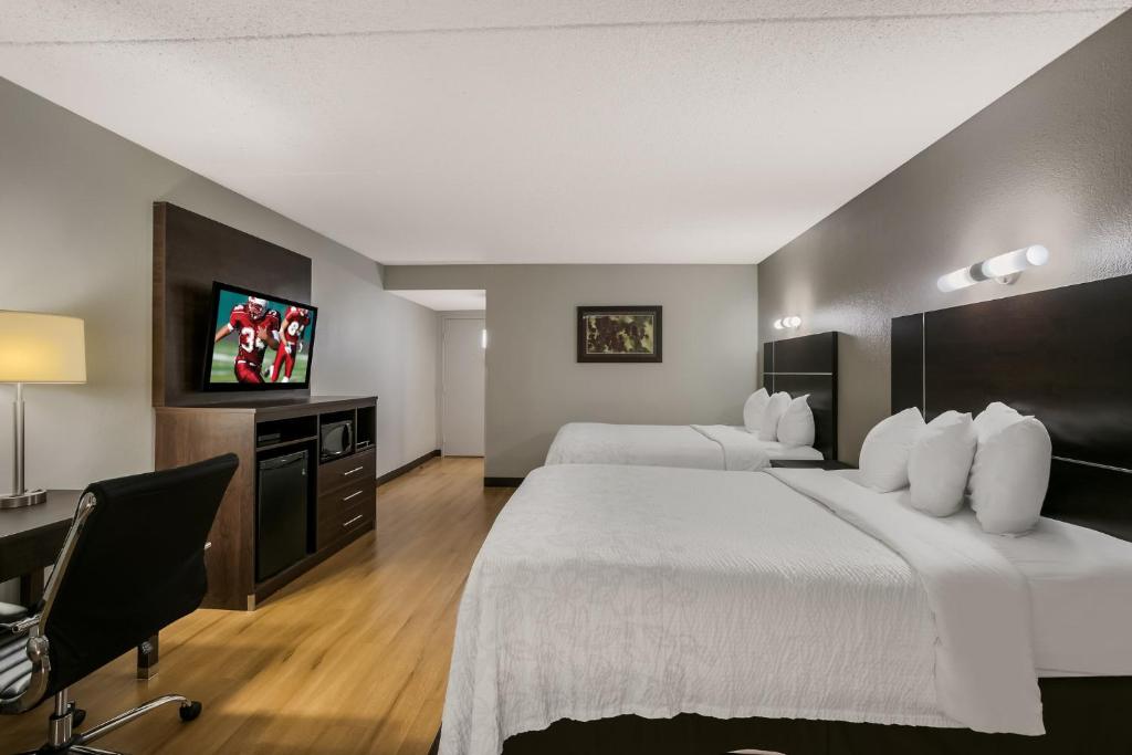 诺克斯维尔Red Roof Inn PLUS+ & Suites Knoxville West - Cedar Bluff的酒店客房设有两张床、一张桌子和一台电视。