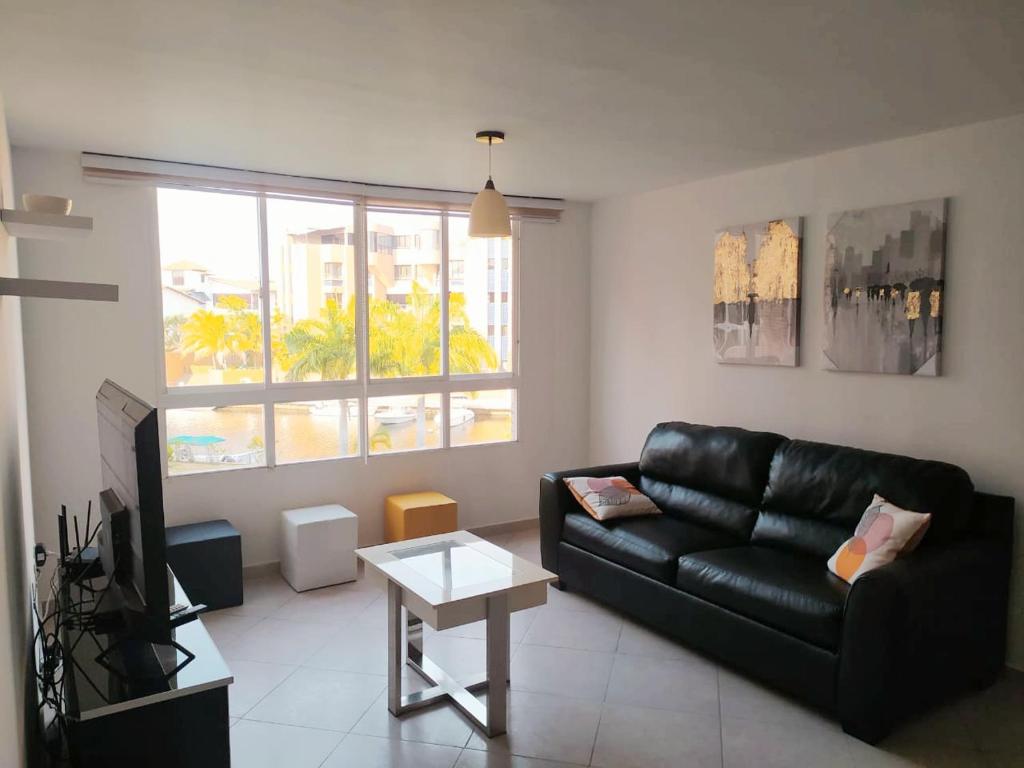 El Morro de BarcelonaConfortable apartamento en Marina del Rey Lecheria的客厅配有黑色真皮沙发和电视