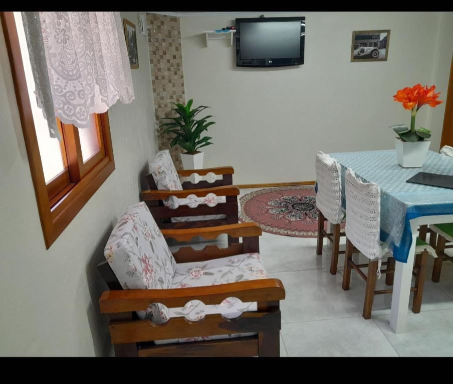 格拉玛多Casa e Flat Conforto Gramado的客厅配有桌椅和电视。