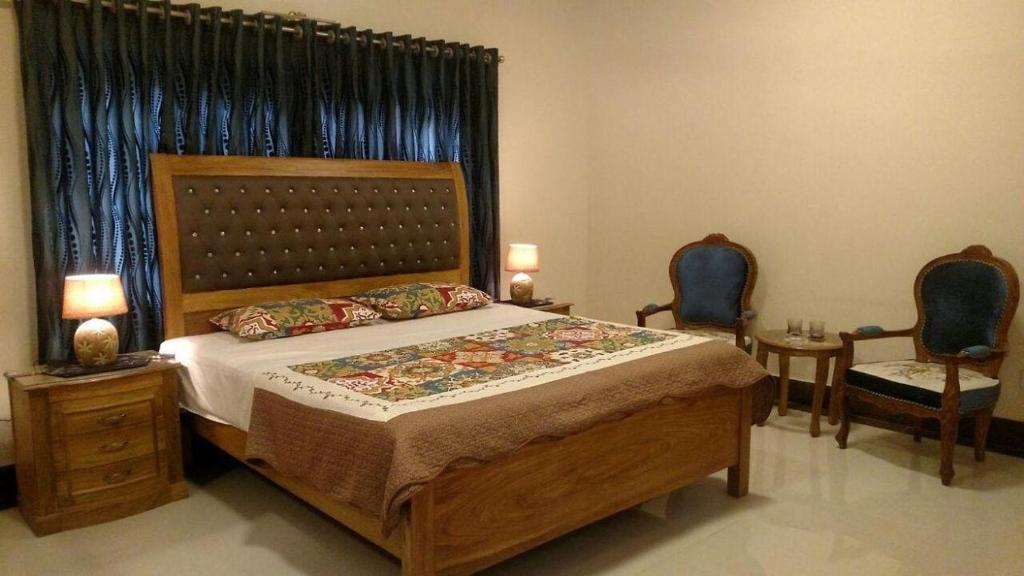 卡拉奇Hotel Inn PECHS的一间卧室配有一张大床和两把椅子