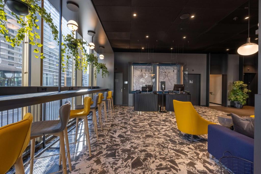 欧普菲康Radisson Hotel & Suites Zurich的一间设有黄色椅子的餐厅和一间酒吧
