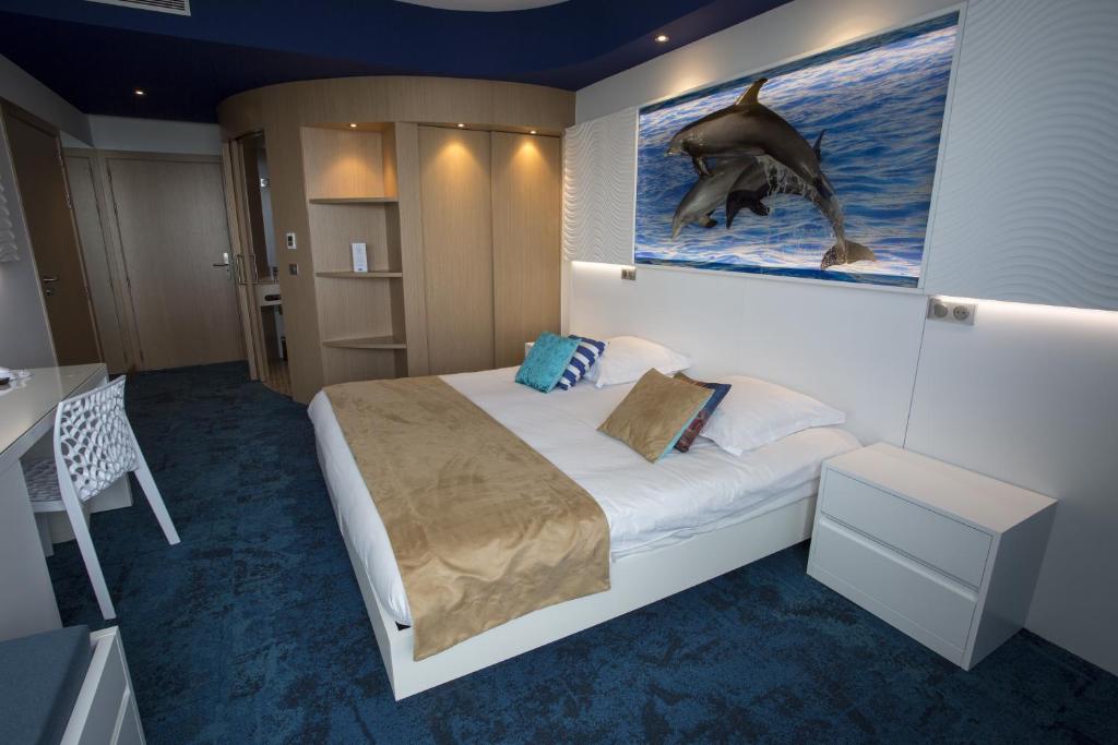 昂蒂布Marineland Hôtel的一间卧室,配有一张床和一张海豚的照片