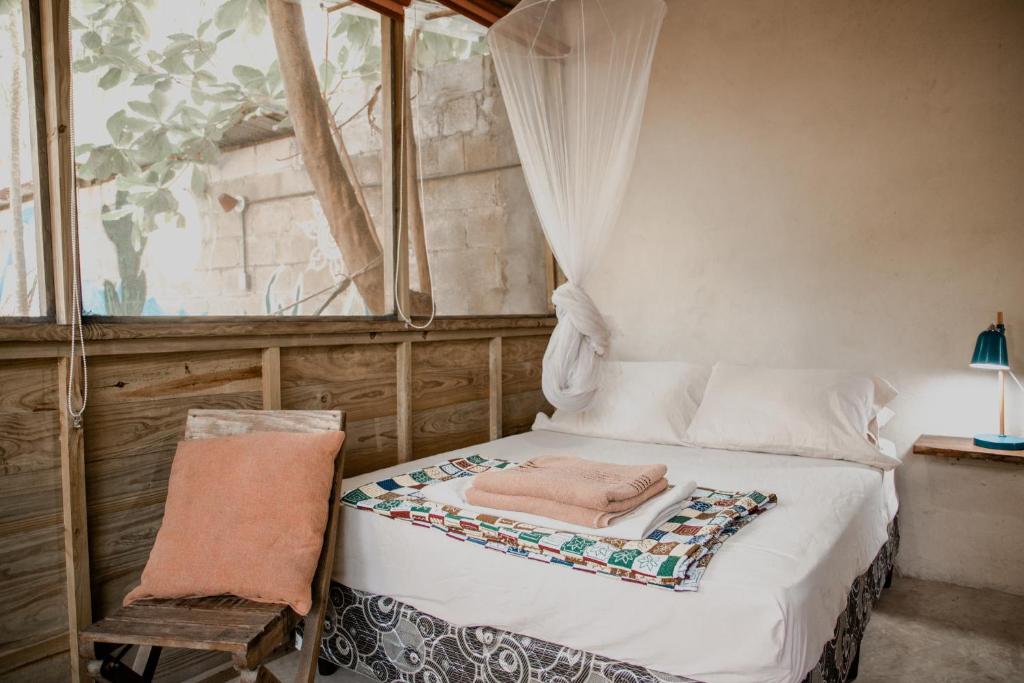 El Paredón Buena VistaCasa Austera的一间卧室配有一张带椅子的床和一扇窗户