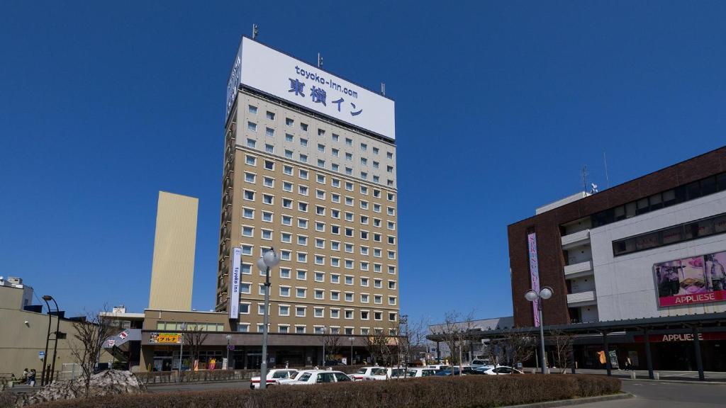 弘前市Toyoko Inn Hirosaki Ekimae的一座高大的建筑,上面有标志