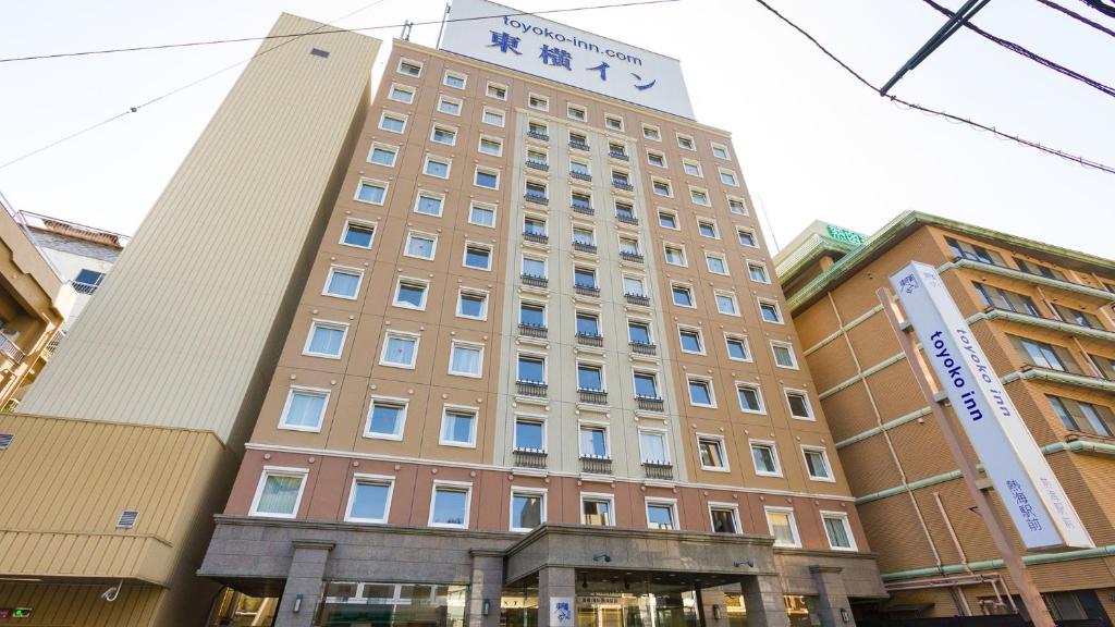 热海热海站前东横旅馆(Toyoko Inn Atami Ekimae) 的一座高大的建筑,上面有标志