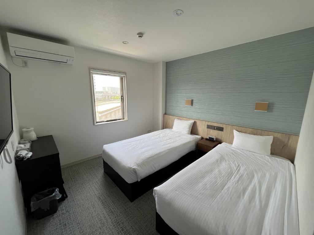 泉佐野Plaza In Kanku Hotel的酒店客房设有两张床和窗户。