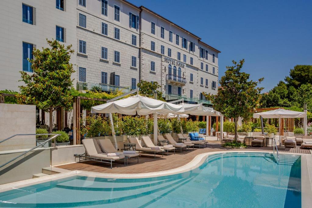斯普利特斯普利特公园酒店的酒店旁的游泳池配有椅子和遮阳伞