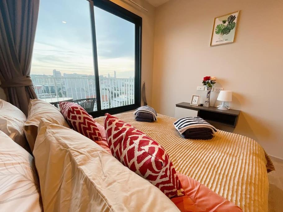 芭堤雅市中心BASE Central PATTAYA Long Balcony with Infinity Pool & Free Netflix!的窗户间内的一张带枕头的床