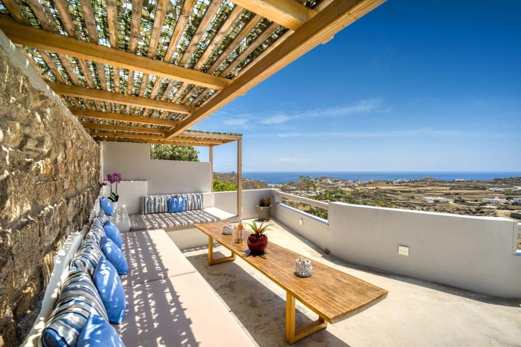 米克诺斯城Overview Mykonos Apartments的阳台配有木桌和蓝色枕头。