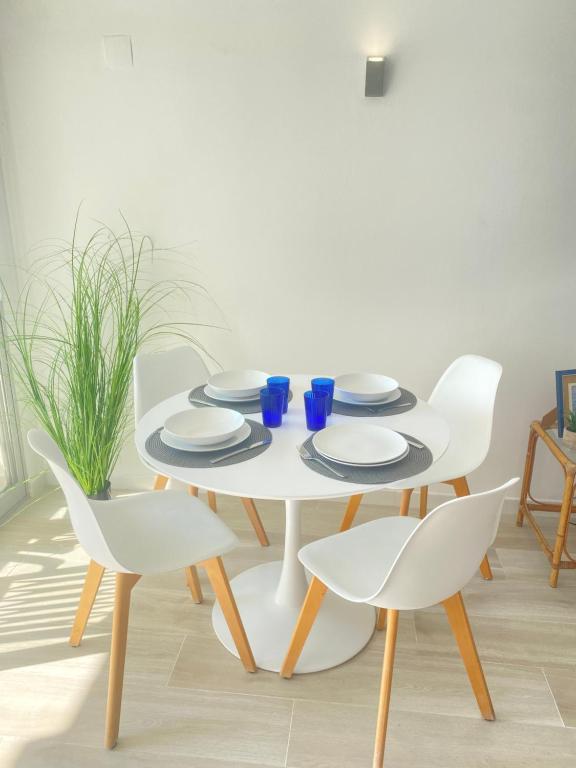 佩尼斯科拉NUEVO !!! Apartamento Peñíscola Playa con piscinas y tenis的白色桌子、白色椅子、桌子、盘子和蓝玻璃杯