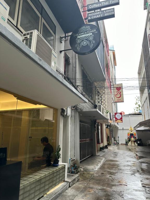 曼谷Dreamcatcher Bangkok的坐在商店窗户上的男人