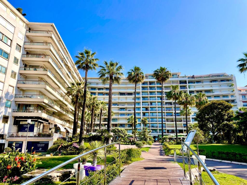 戛纳Agence des Résidences - Appartements privés du 45 CROISETTE- Prestige的棕榈树和走道的大型公寓大楼