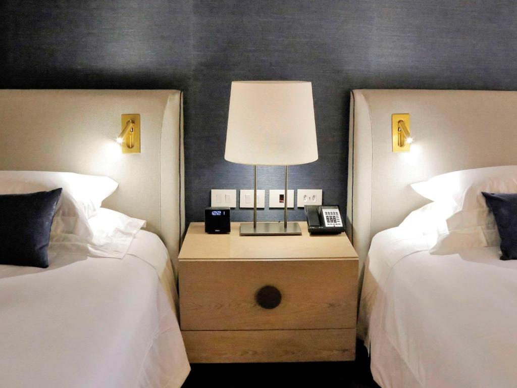 里约热内卢Fairmont Rio de Janeiro Copacabana的一间卧室配有两张床和床头灯。
