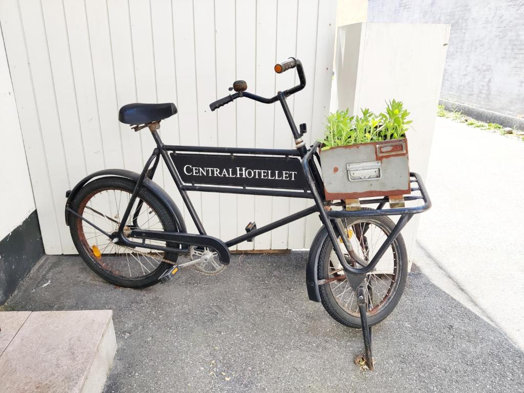克厄CentralHotellet的停在建筑物旁边,放着一篮子的植物的自行车