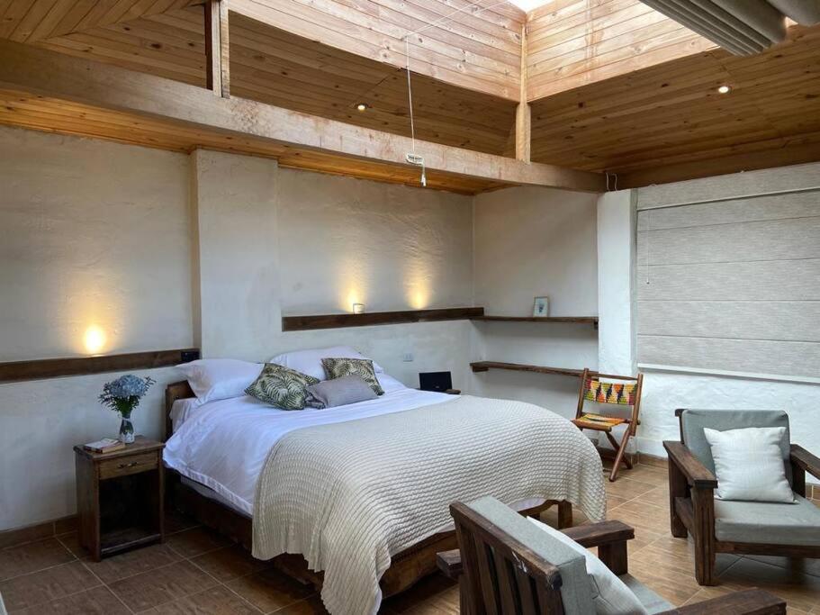 CoguaLa Arboleda, Refugio的一间卧室设有一张大床和木制天花板