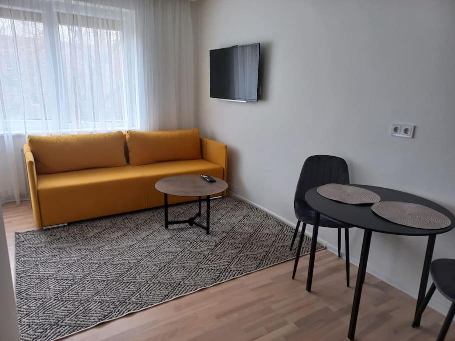 克莱佩达City center apartment的客厅设有黄色的沙发和2张桌子