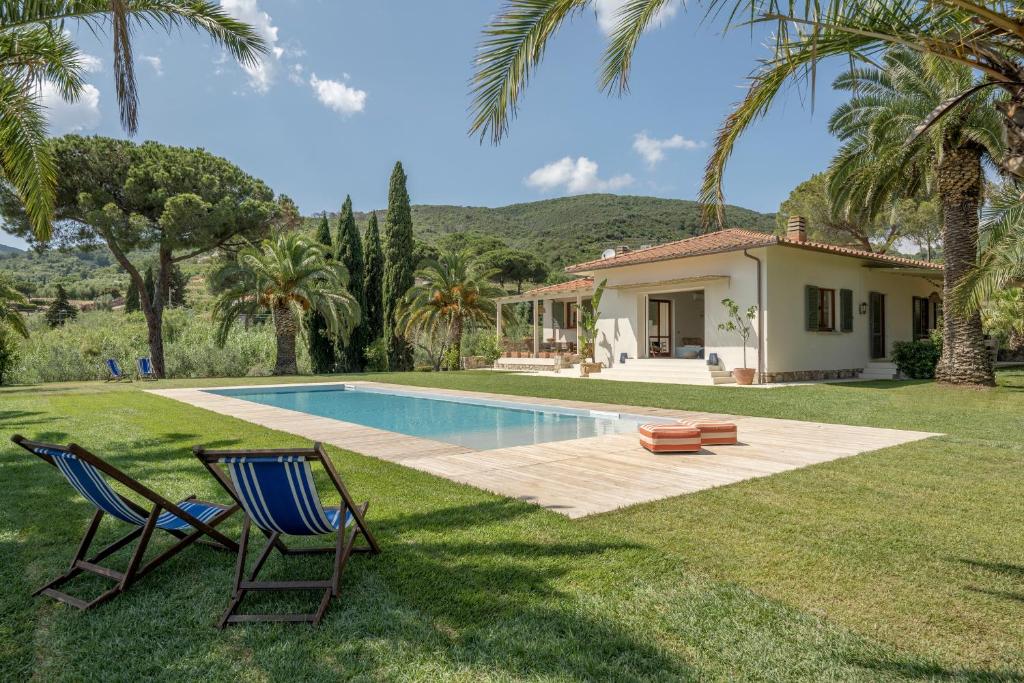 卡波利韦里Villa Elle Exclusive Isola d'Elba的庭院内带游泳池和两把椅子的房子