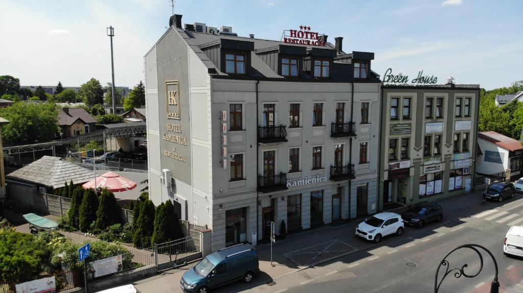 谢德尔采卡米尼卡酒店的一座白色的建筑,前面有汽车停放