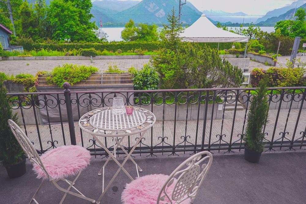 DärligenLake Guest Haus的阳台上配有带粉红色软垫椅子的桌子