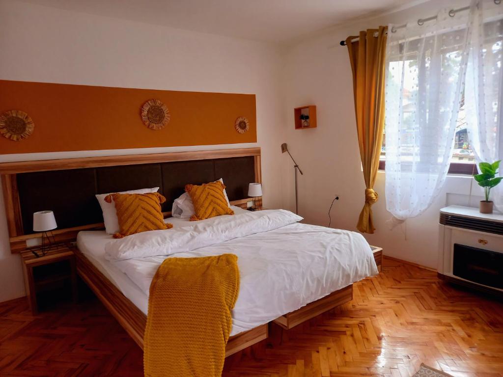 Stari BanovciPrenociste Biki的卧室配有带橙色枕头的大型白色床