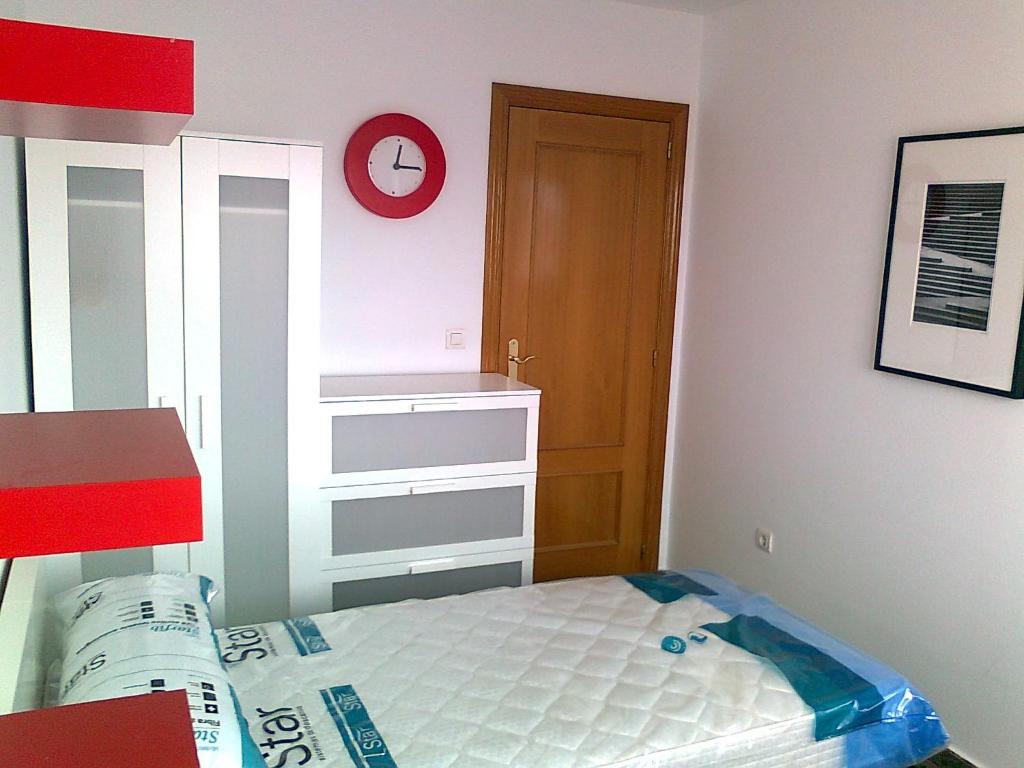 布尔哈索特PISO 4 HABITACIONES BURJASOT的一间小卧室,配有一张床和墙上的时钟