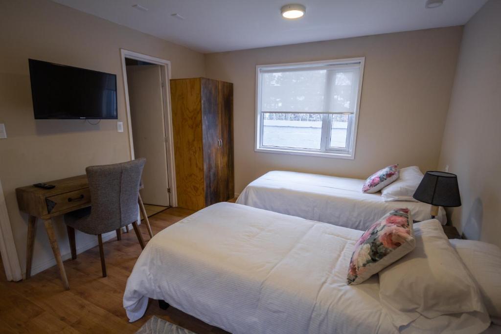 蓬塔阿雷纳斯Departamentos Avenida Colon的一间卧室配有两张床、一张桌子和一台电视。