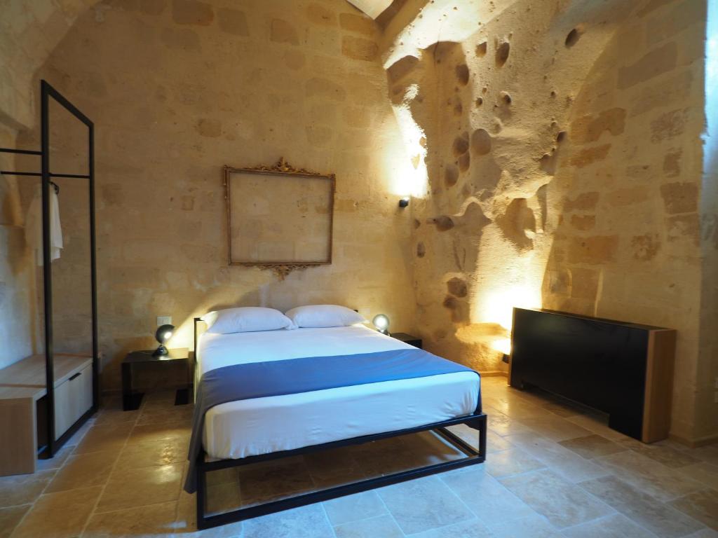 马泰拉Dimore dei Mercanti的一间卧室配有一张床,并在一间客房内配有电视。
