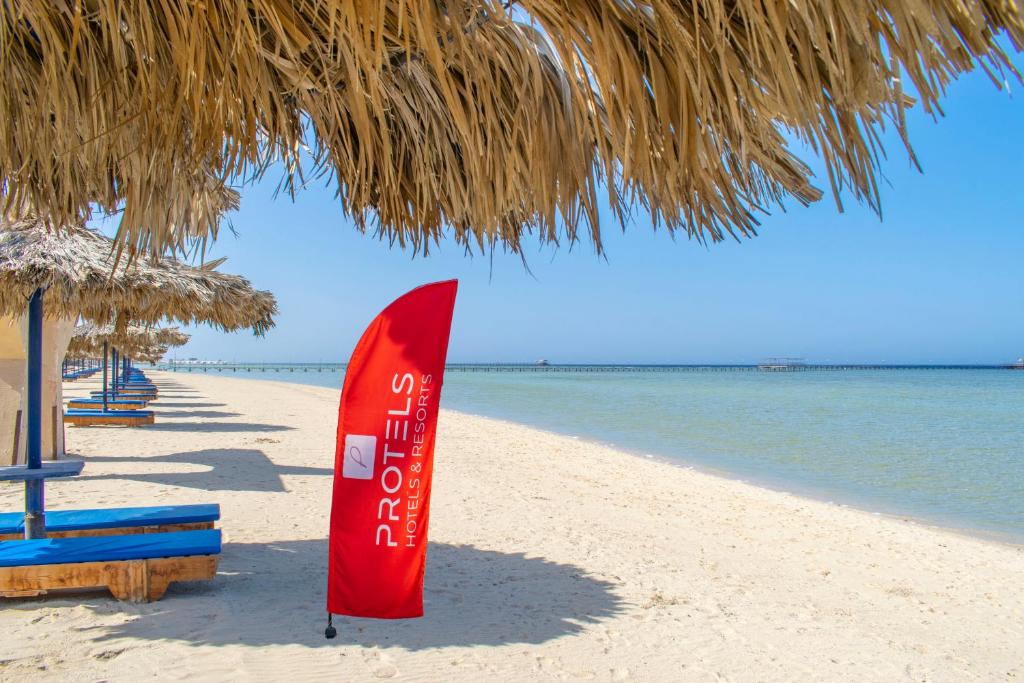 马萨阿拉姆Protels Crystal Beach Resort的海滩上的红冲浪板,在稻草伞下