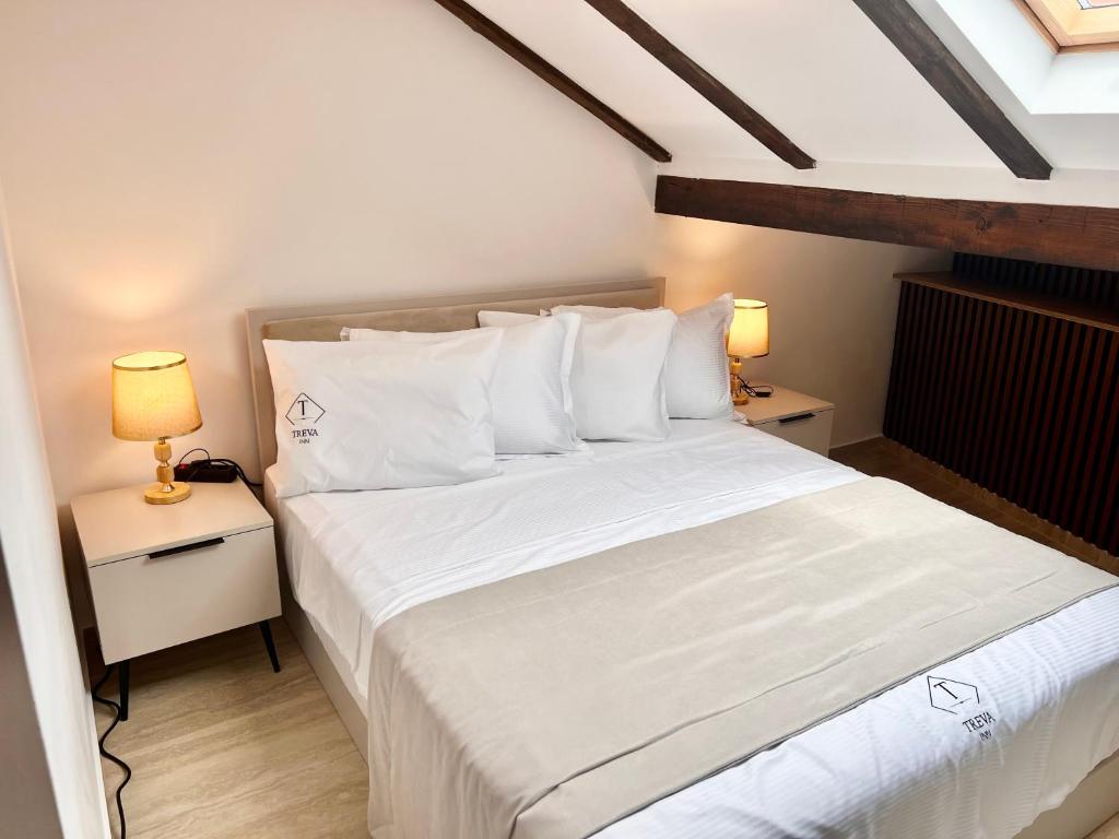 普里兹伦Treva Hotel的一间卧室配有一张带白色床单和两盏灯的床。