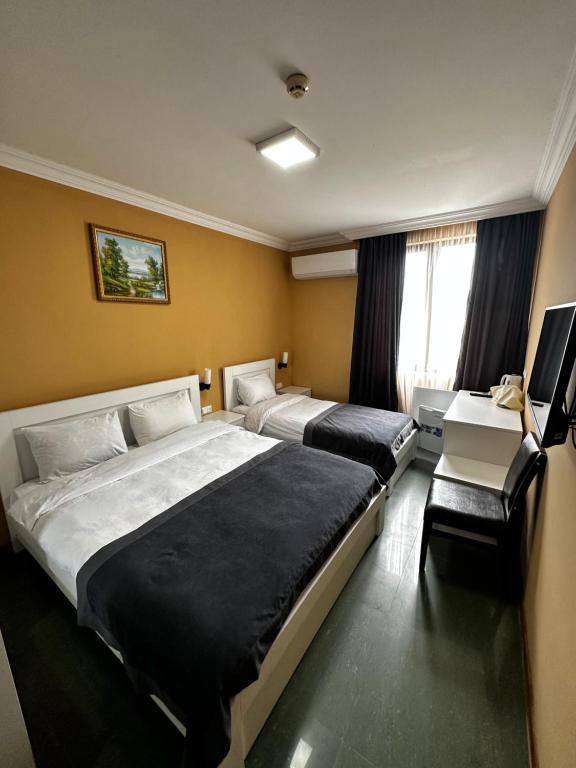 巴统Hotel Brighton的酒店客房配有两张床和一张书桌