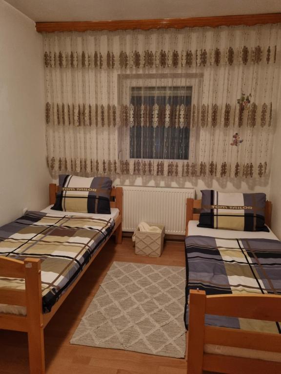 波斯尼亚克鲁帕Ferienwohnung Sabina的一间卧室设有两张床,窗户配有窗帘