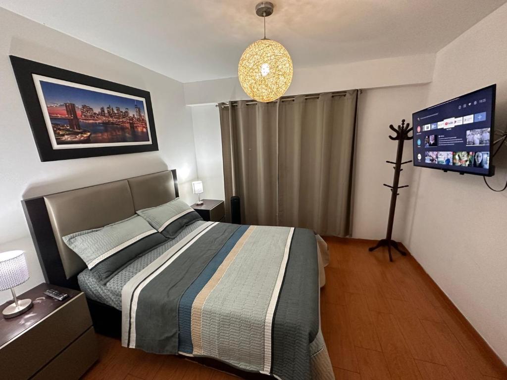 利马Hermoso Departamento en Guardia Civil - Chorrillos的卧室配有一张床,墙上配有电视。