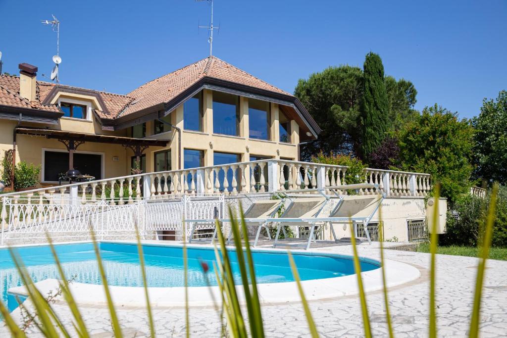 里乔内Villa Rolls - Porzione di Villa con piscina,giardino e parcheggi的房屋前有游泳池的房子
