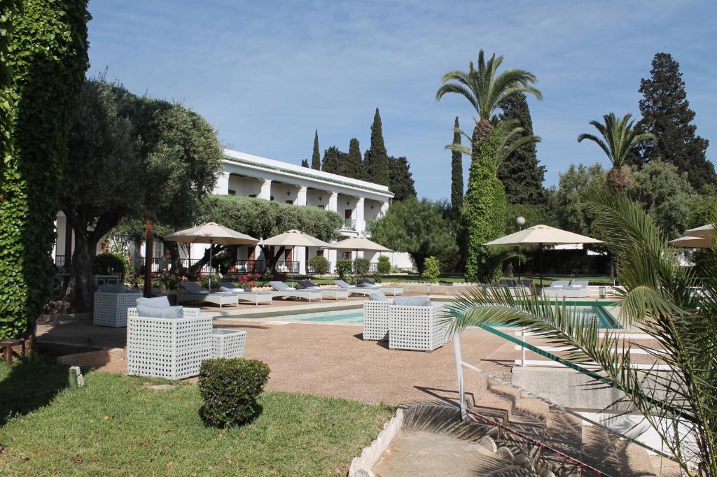 梅克内斯特兰斯兰提克酒店的一个带白色椅子和遮阳伞的游泳池的度假酒店
