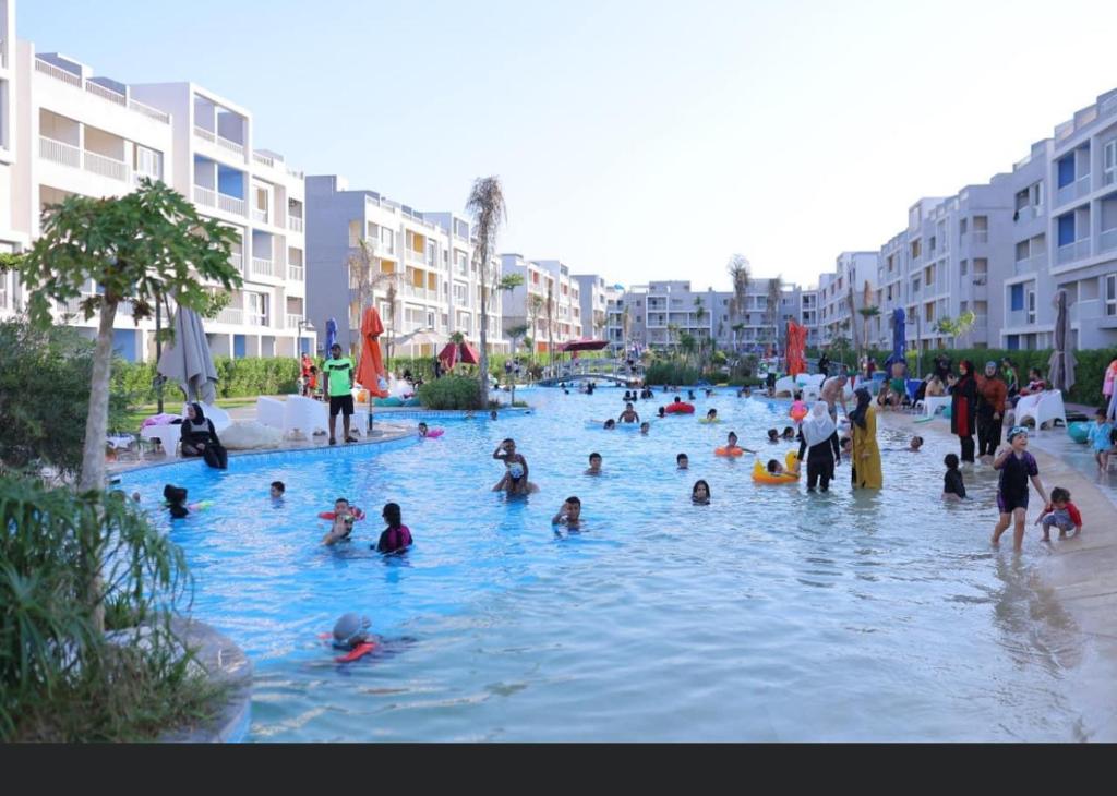 Al Ḩammādشاليه سياحي بمارينا دلتا لاجونز المنصورة الجديدة的一群人在游泳池玩耍