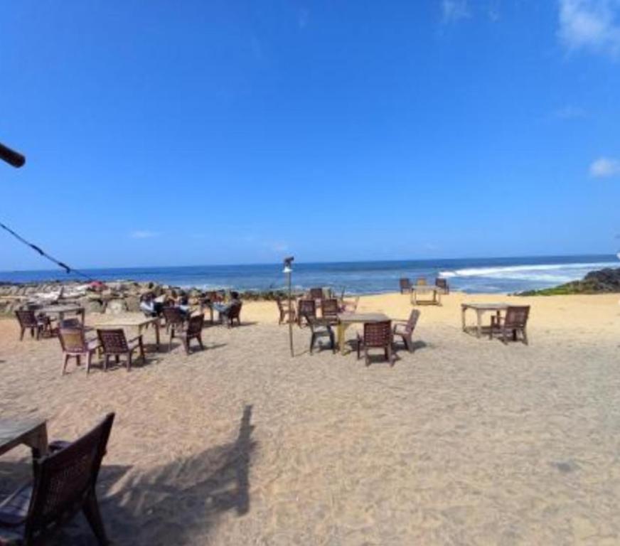 瓦尔卡拉East West Beach Resorts的海滩上的一组桌椅