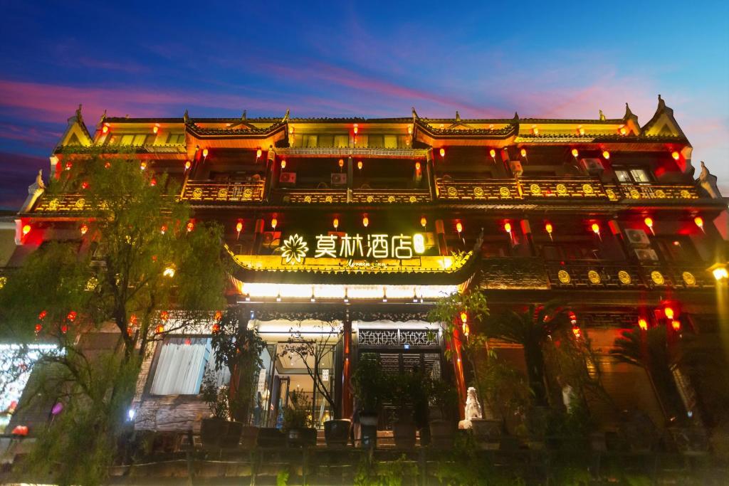 凤凰莫林风尚酒店凤凰古城沱江店的一座在晚上有灯光的亚洲建筑