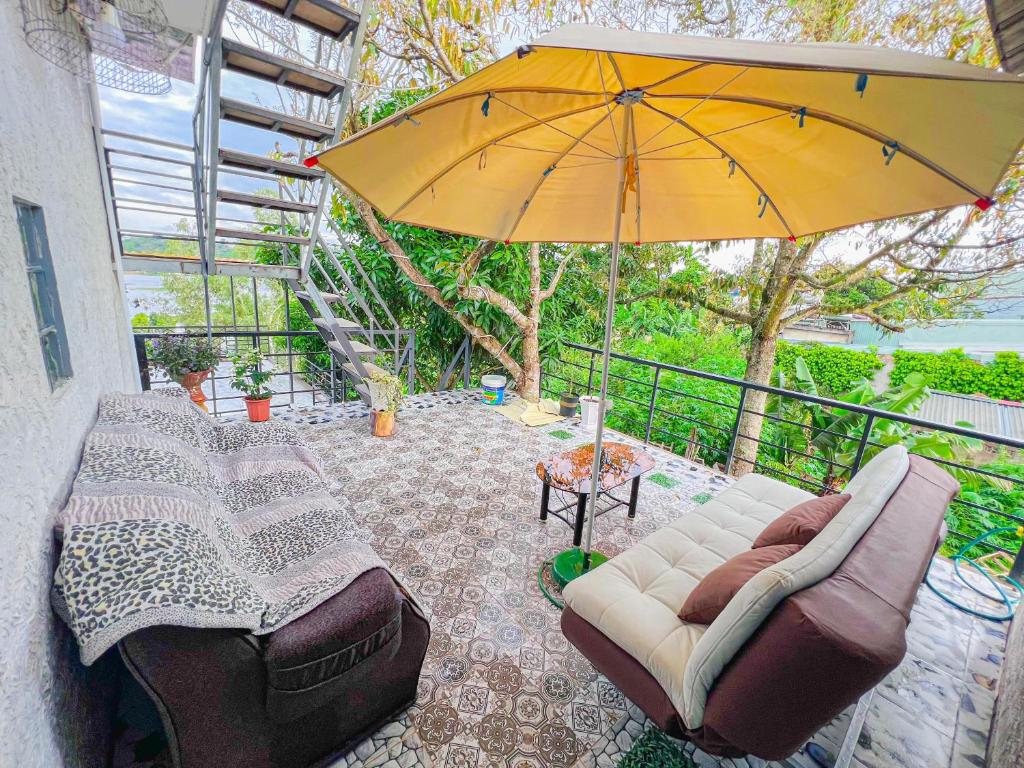 波来古市Gió Homestay - Pleiku的一个带沙发和遮阳伞的庭院